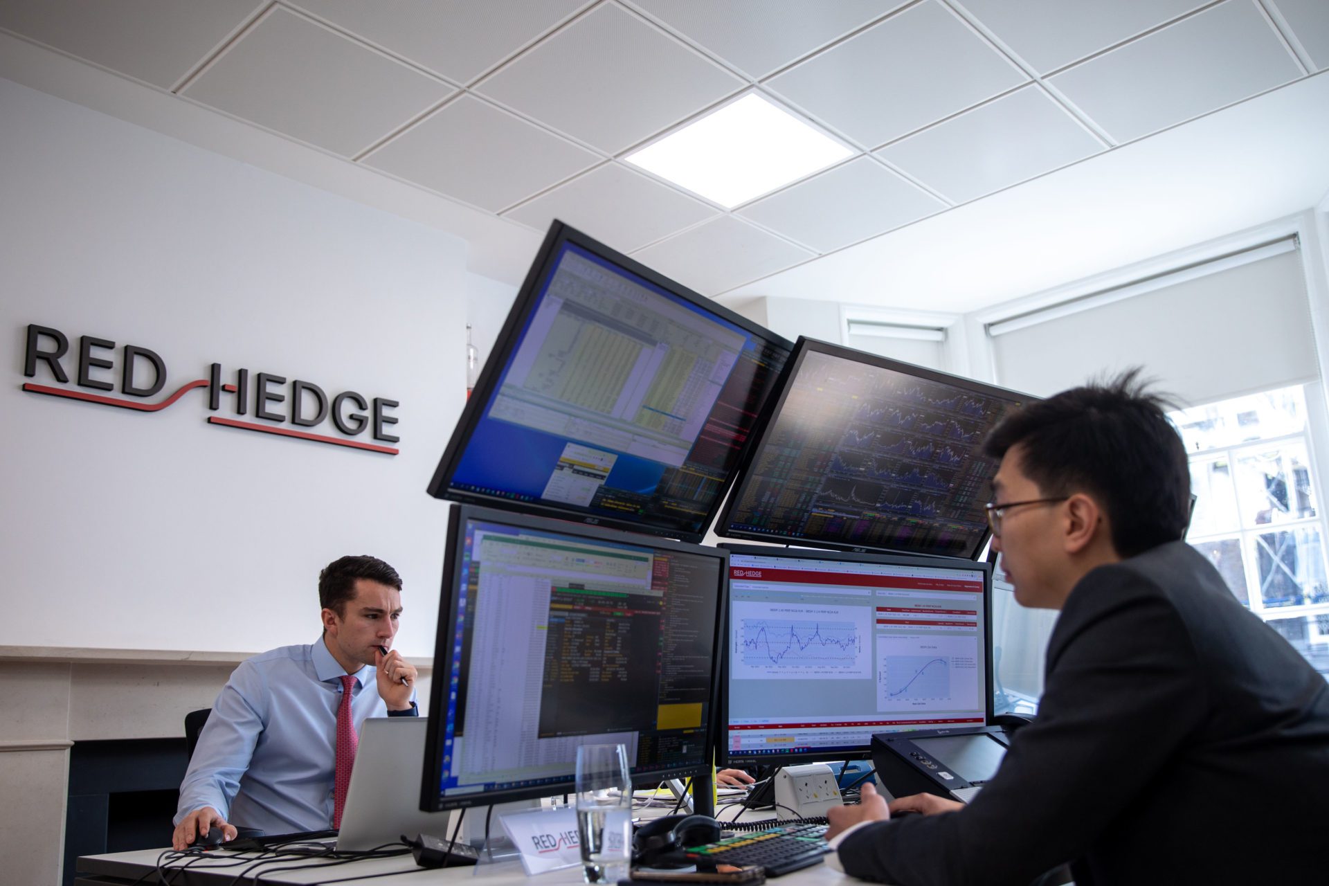 Two men in suits looking at trading monitors